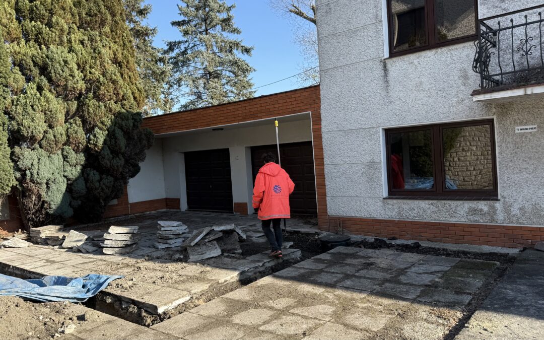 geodeta wykonujący pomiary geodezyjne przy budynku podczas przygotowania mapy do celów projektowych