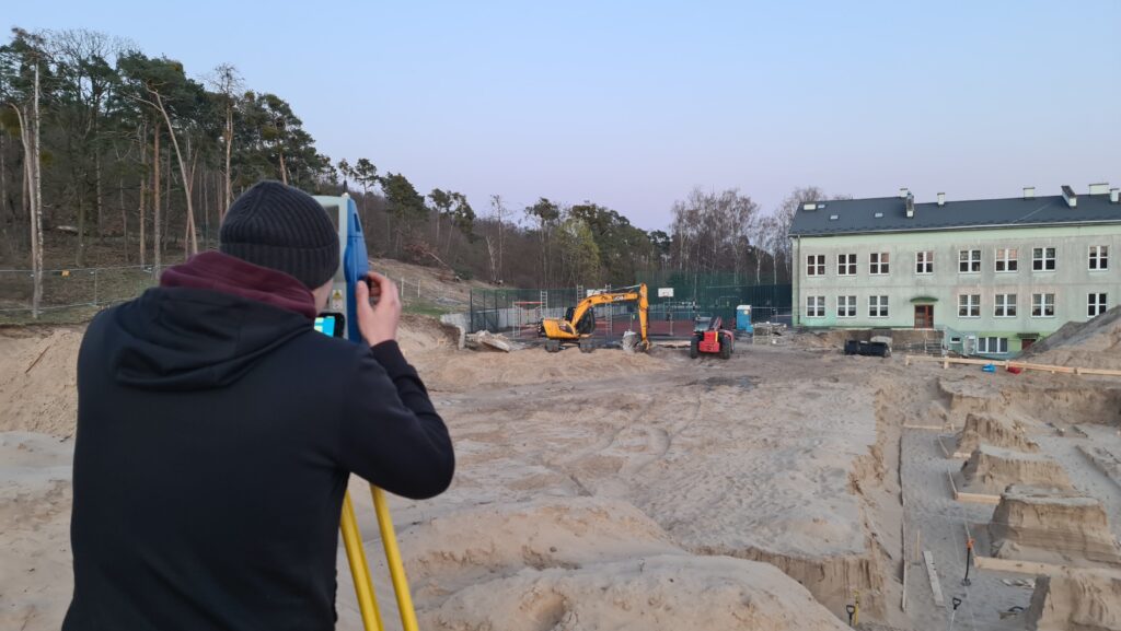 Geodeta na placu budowy wykonujący pomiary tachimetrem – przygotowanie do realizacji fundamentów oraz kontrola zgodności robót z projektem.